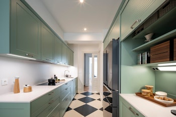 Una cocina verde con zona de desayunos y office