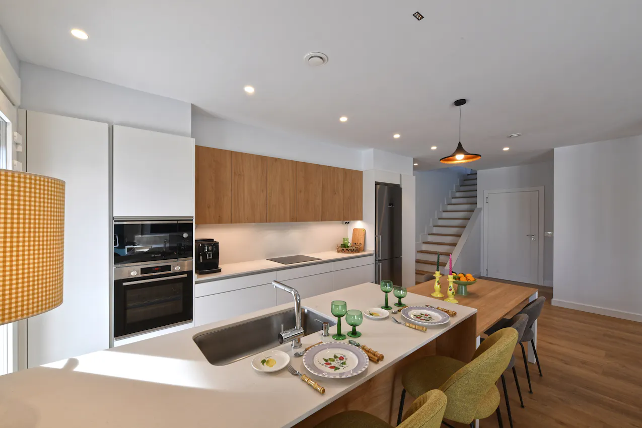 Cocina abierta con peninsula y mesa blanca y madera - CJR